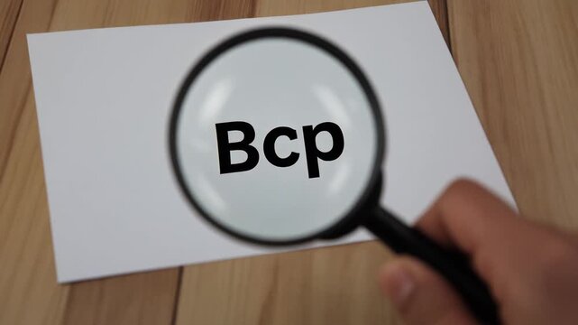 A blank sheet of paper on a wooden surface with a magnifying glass, BCP   Business Continuity Plan