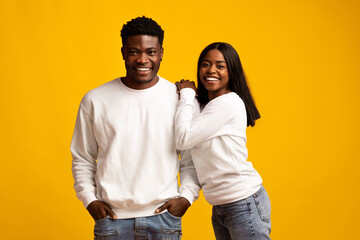 Obraz premium A young couple stands close, smiling broadly. The man wears a white sweatshirt and jeans while the woman is in similar attire.