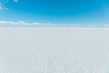 A large, empty, snow-covered field with a bright sun shining down on it