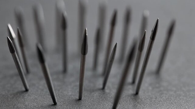 Macro view of sharp metal spikes sticking out of a grey surface.