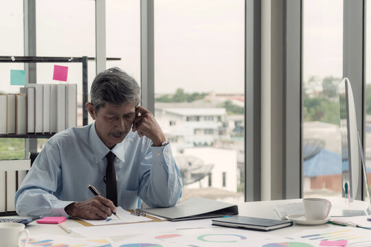 Seasoned man manager with a thoughtful expression reviewing paperwork and graph dedicated to his task in an office setting.