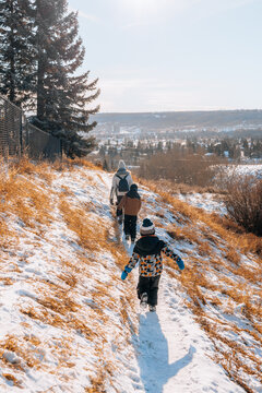 Woman and children walking on a snowy footpath in a park on a sunny winter day