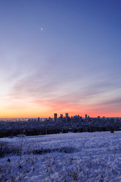 The outline of downtown Calgary at dawn with the moon in the sky