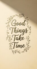 Inspirational quote on a wall that reads 'Good Things Take Time' surrounded by a delicate floral wreath design in a soft, neutral setting