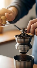 Close-up of a person using a manual coffee grinder to prepare freshly ground coffee beans in a modern kitchen setting