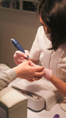 Manicure technique. Nail treatment. Female beautician hand in gloves removing cuticle with professional milling machine to create shape.