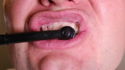 Close-up macro video of a man cleaning his teeth with an electric toothbrush