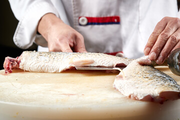 On a white cutting board, the chef demonstrates his exquisite knife skills in cutting and slicing sashimi and fresh fish.