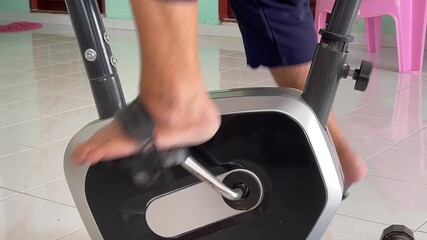 Close-up of a senior’s feet continuously pedaling a stationary exercise bike, showing home fitness, active lifestyle, and healthy aging in motion.