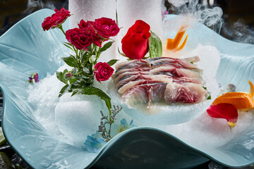 Arrange the glistening, white slices of fresh fish on a black round porcelain plate.