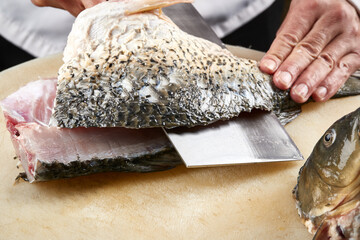 On a white cutting board, the chef demonstrates his exquisite knife skills in cutting and slicing sashimi and fresh fish.