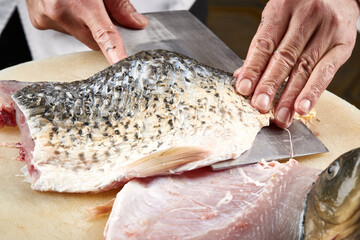 On a white cutting board, the chef demonstrates his exquisite knife skills in cutting and slicing sashimi and fresh fish.