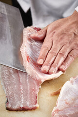 On a white cutting board, the chef demonstrates his exquisite knife skills in cutting and slicing sashimi and fresh fish.