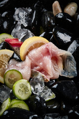 Arrange the glistening, white slices of fresh fish on a black round porcelain plate.