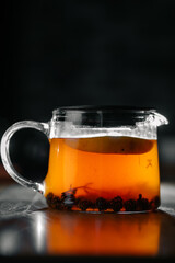 Close-up of glass teapot with hot herbal tea and lemon slice
