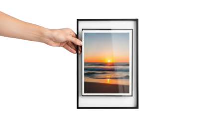 A hand holding a framed photograph of a sunset on a