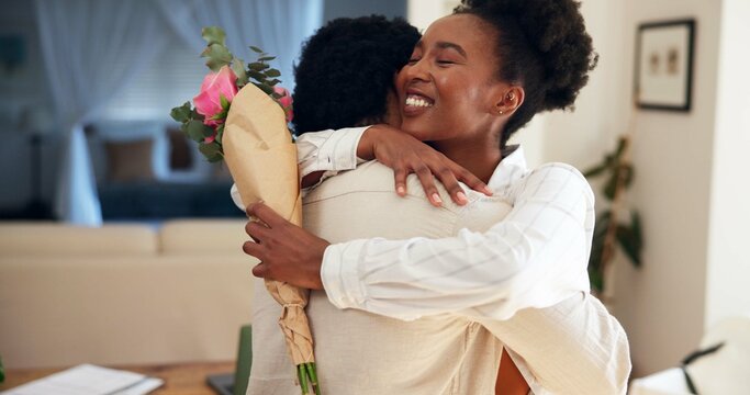 Flowers, hug and romance with black couple in home living room together for anniversary or love. Bonding, roses and smile of woman embracing man in apartment for celebration, milestone or thank you