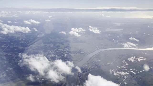 View from airplane window flying over Japan &ndash; clouds and mountain landscape under clear blue sky
