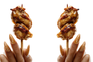 Two skewers of cooked meat are held up by manicured hands against a black backdrop