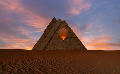 Hot air balloon flying over Giza Pyramid Complex at amazing sunset - Cairo, Egypt