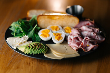 Avocado toast with fried egg, ham, and greens served for breakfast