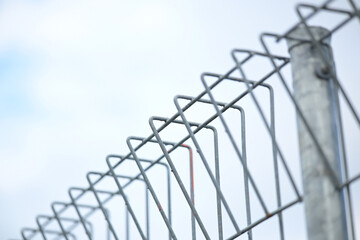 Modern metal fence detail against sky background