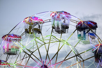 Bright Ferris wheel at dusk with colorful lights glowing