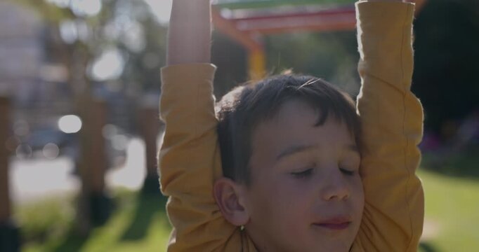 Young boy looking worried and lets go of monkey bars - close up on hands
