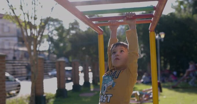 Young boy learning to use the monkey bars in park on sunny day