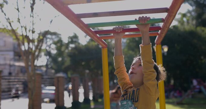 Young boy making his way across the monkey bars in park