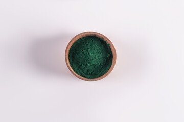 Wooden bowl with green powder of organic spirulina product on a white background. top view. A copy of the space. Detox. superfood.