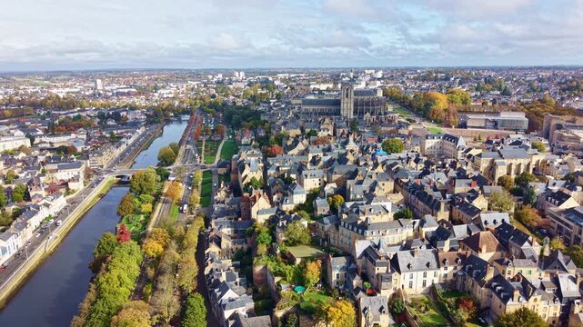Drone panning shot from left to right over Le Mans, showing the Sarthe River, the old town and the Saint-Julien Cathedral surrounded by autumn trees.