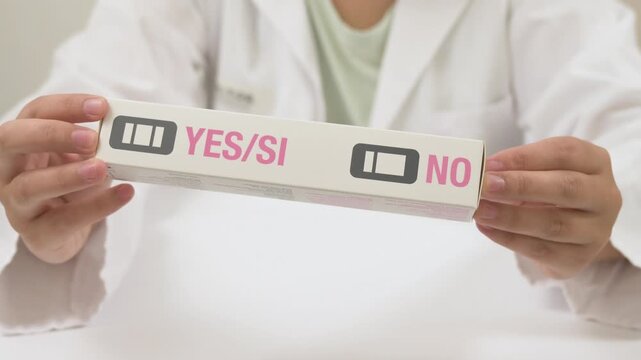 Female doctor in a white coat holding a positive pregnancy test kit in a medical office