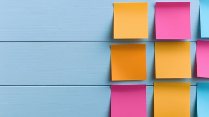 Brightly colored sticky notes adhere to a light blue wooden surface leaving ample copy space on the left