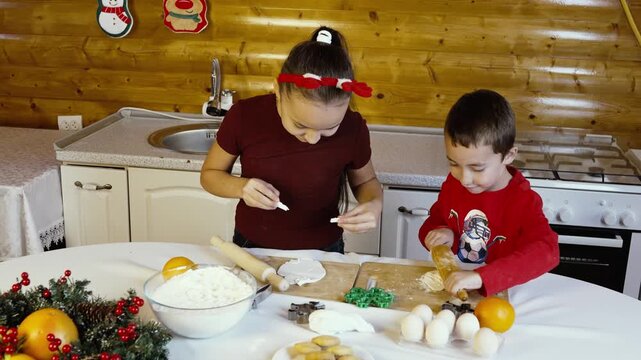The children are decorating Christmas cookies together in the kitchen
