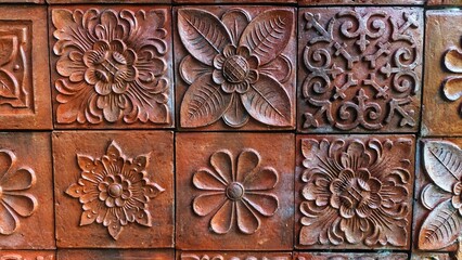 A brick wall featuring typical Balinese carvings. The intricate designs are set in square tiles, showcasing traditional craftsmanship.