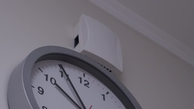 A white, plastic doorbell chime is mounted on a wall next to a clock. The doorbell rings with a soft, pleasant ding-dong sound.