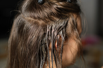 Naklejka premium Hair Coloring Process Taking Place on a Young Womans Hair in a Well-Lit Salon Setting