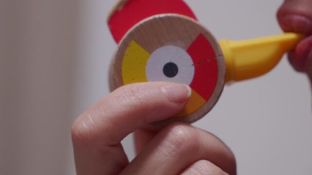 A wooden toy whistle with a yellow plastic mouthpiece is blown. The whistle emits a long, sustained, high-pitched sound.