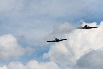 Two Propeller Aircraft Flying in Formation Through Cloudy Sky