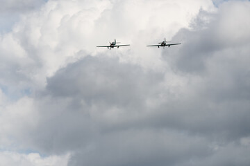 Two Propeller Aircraft Flying in Formation Through Cloudy Sky