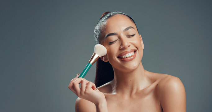 Makeup, brush and and woman in studio for cosmetics, contouring and beauty treatment. Happy, blush and female person with tool for blending, application and cosmetology routine by gray background.