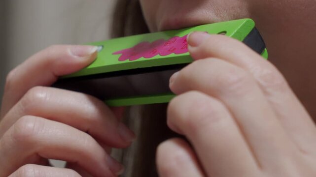 Distinct Note: Hands Hold Wooden Harmonica, Playing a Single Musical Tone.