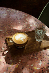 Hot coffee latte with latte art milk foam in cup mug on marble floor desk As breakfast In a coffee shop at the cafe, during business work concept