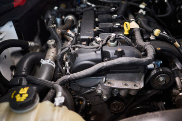 Fototapeta premium Car engine detail, Polished engine components with workshop lighting detail, Precise view of polished intake runners and textured cover in professional automotive setting