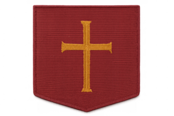 Red fabric embroidered patch depicting golden christian cross, shield shape symbolizing religion and spiritual protection, transparent background