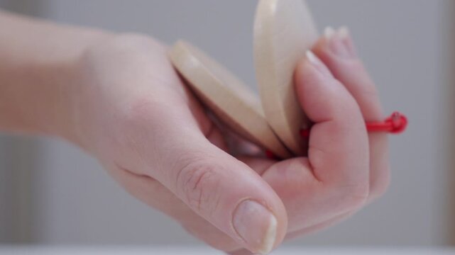 A hand claps two wooden castanets together. The musical instrument produces a sharp, rhythmic wooden clacking sound.
