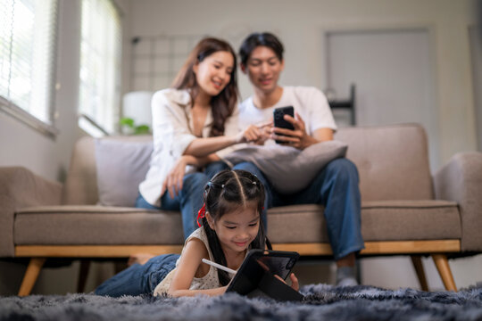Asian family using digital devices together in living room