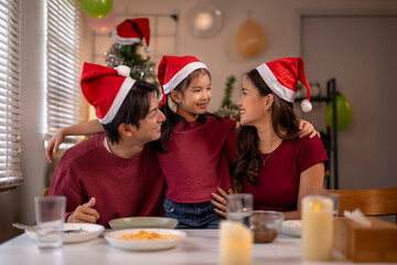 Asian family celebrating christmas dinner in santa hats