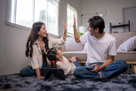 Asian family parents high fiving celebrating success at home